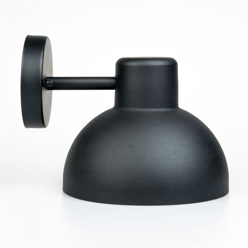 Sort væglampe hviler på en kort arm, skærmen vender nedad; mat sort metalfinish med rund vægplade til montering, placeret mod en ensartet hvid baggrund.