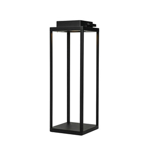 En høj, sort metallanterne står fritstående; dens fire slanke søjler omslutter en åben midte, med en indbygget lyskilde øverst, placeret mod en ren, hvid baggrund.