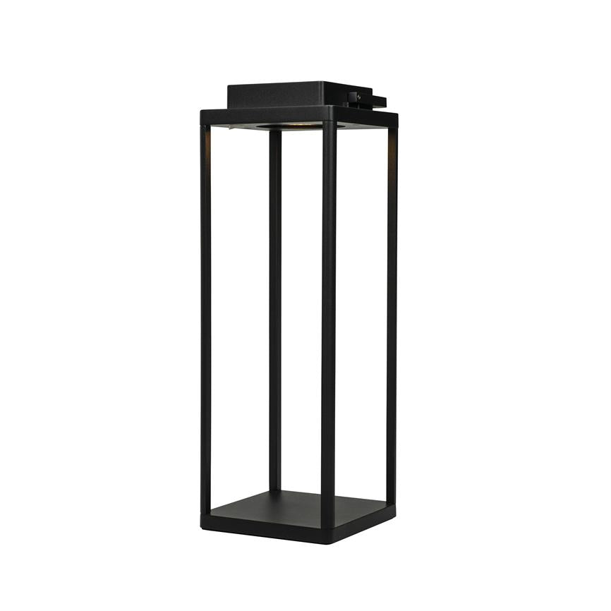 En høj, sort metallanterne står fritstående; dens fire slanke søjler omslutter en åben midte, med en indbygget lyskilde øverst, placeret mod en ren, hvid baggrund.