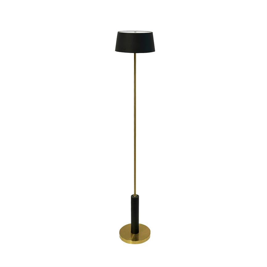 Gulvlampe står oprejst med slankt messingstativ, sort cylindrisk fod og sort lampskærm øverst, placeret mod en ensartet hvid baggrund.