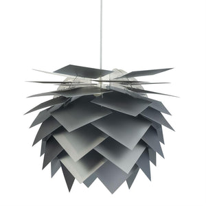 Hængende loftslampe formet af overlappende matte, firkantede metalplader, som danner en koglelignende kugle; ophængt i en tynd stang mod en ensartet hvid baggrund.