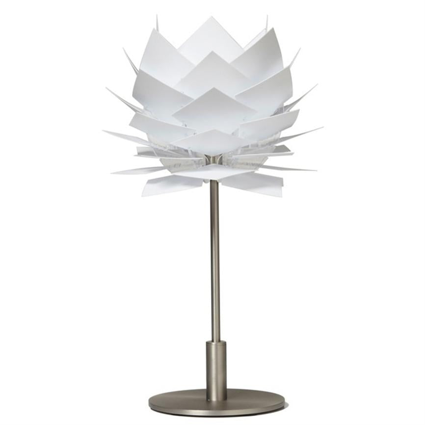 Bordlampe formet som en lagdelt blomst med hvide, kvadratiske "blade" i ringe; den står på en slank metalstang med rund metalfod foran en hvid studiebaggrund.