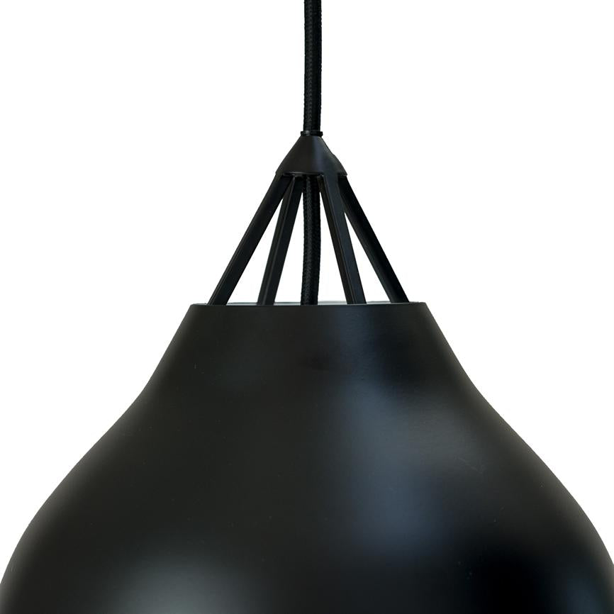 Sort metal pendellampe hænger i en tekstilbeklædt ledning; konisk skærm med fem smalle støttestænger øverst. Tæt, hvid baggrund fremhæver lampens matte overflade.