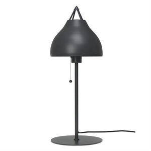 Bordlampe med mørkegrå afrundet skærm hænger over en lodret stang, betjenes via trækknap; placeret på rund fod med synlig ledning, mod neutral hvid baggrund.