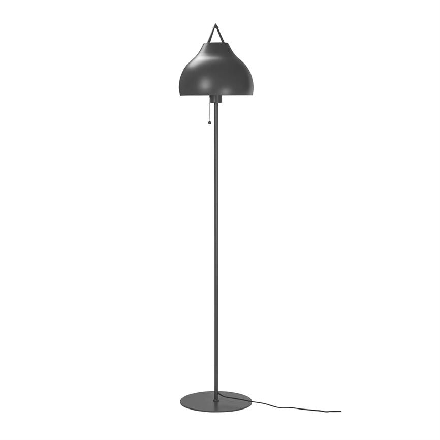 Gulvlampe står oprejst med en buet, mat sort lampskærm; en tynd stang forbinder skærm og rund fod, en trækknap hænger under skærmen, ledning ligger på hvid baggrund.