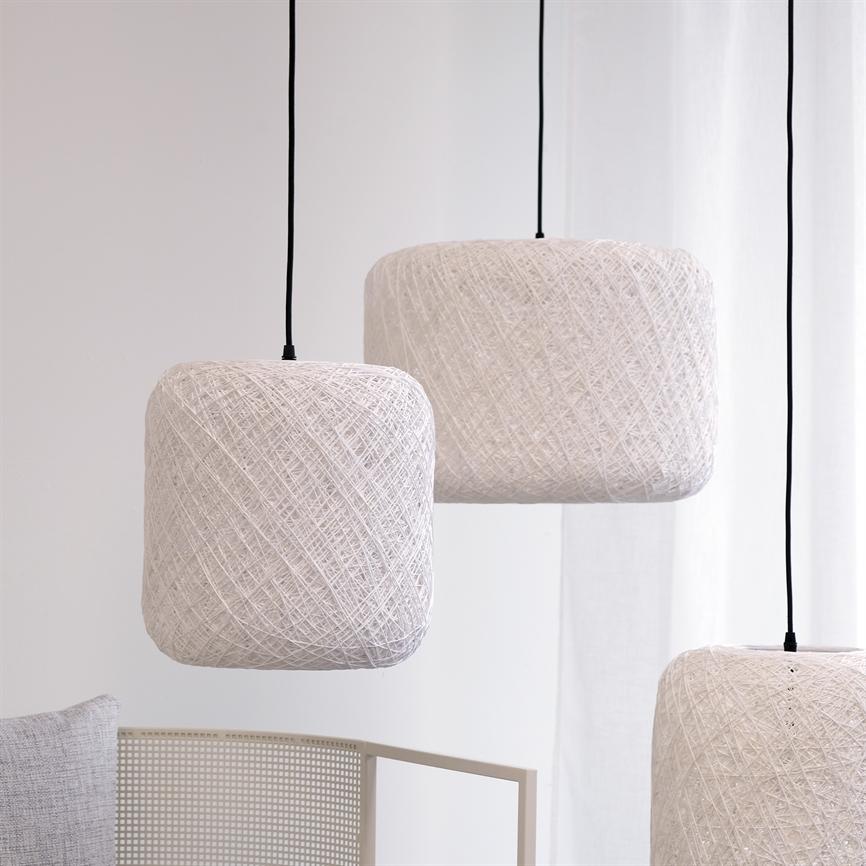 Tre hvide, trådindpakkede pendler hænger i sorte ledninger over et lyst rum med hvidt gardin og en lysegrå stolryg, der antyder en minimalistisk indretning.