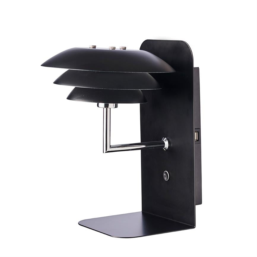 En sort væglampe med tredelt, lagdelt skærm monteret på en rektangulær plade; en krom arm bærer skærmen, med indbygget USB-port og afrundet tænd/sluk-knap i et minimalistisk design.