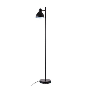 Sort gulvlampe står oprejst med høj, slank stang og nedadvendt kuppelskærm; rund fod og løst liggende ledning på hvid baggrund.