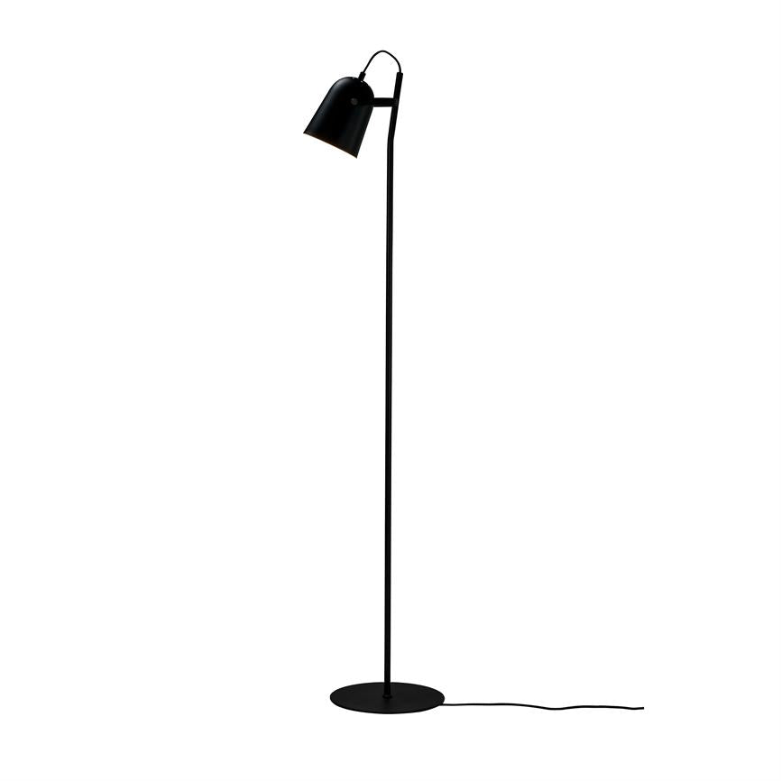 Sort gulvlampe står opret, med skærm rettet nedad, på en rund fod; sort ledning strækker sig ud over en ensartet hvid baggrund.