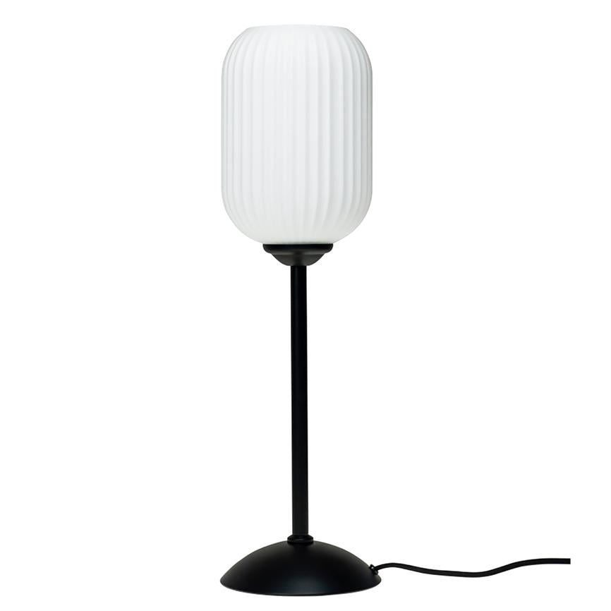 En bordlampe med ribbet, hvid cylindrisk skærm, står på en slank sort stang og rund sort fod med synlig ledning på hvid baggrund.