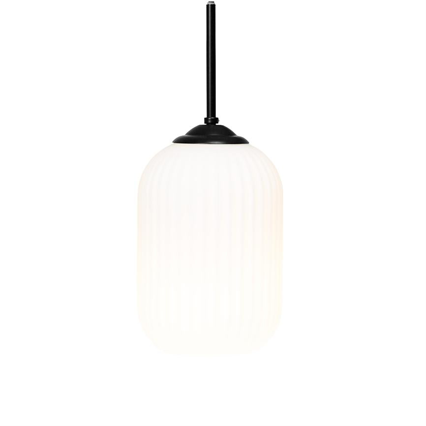 En hængelampe med sort metalstang og -top, der holder en oplyst, hvid, ribbet glaskuppel i cylinderform og udsender et blødt lys; lampe hænger frit mod en neutral, hvid baggrund.