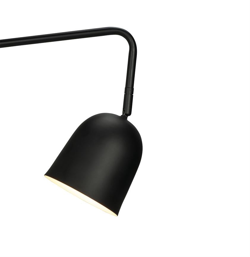 Sort metalskærmslampe hænger fra en buet arm, skærmen er vippet nedad og udsender varmt lys; enkel, minimalistisk design mod en ensartet hvid baggrund.