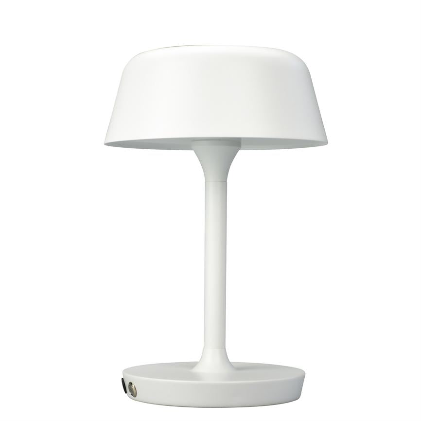 En hvid bordlampe står oprejst; skærmen buer let udad, monteret på en slank stang og rund fod; neutral hvid baggrund uden andre genstande.