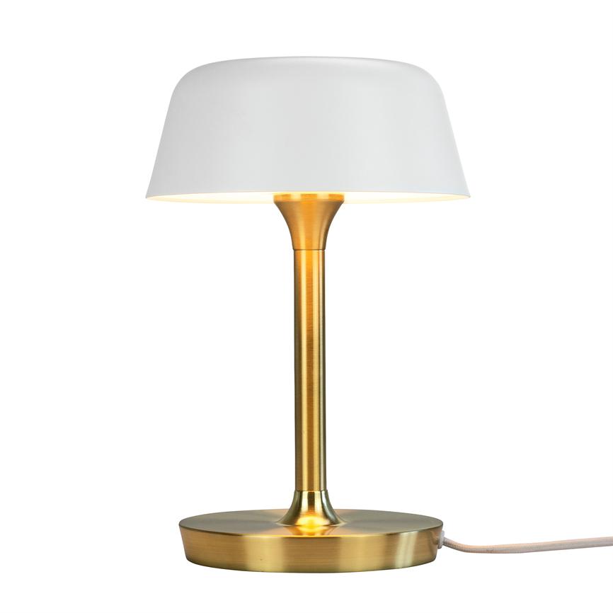 Bordlampe med hvid skærm lyser nedad; slank gylden metalstang og rund fod står på ensartet hvid baggrund, tekstilledning løber ud mod højre.