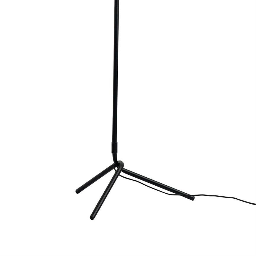 Sort slank gulvlampe står på en trebenet fod; en løs ledning ligger langs gulvet mod højre; neutral hvid baggrund.