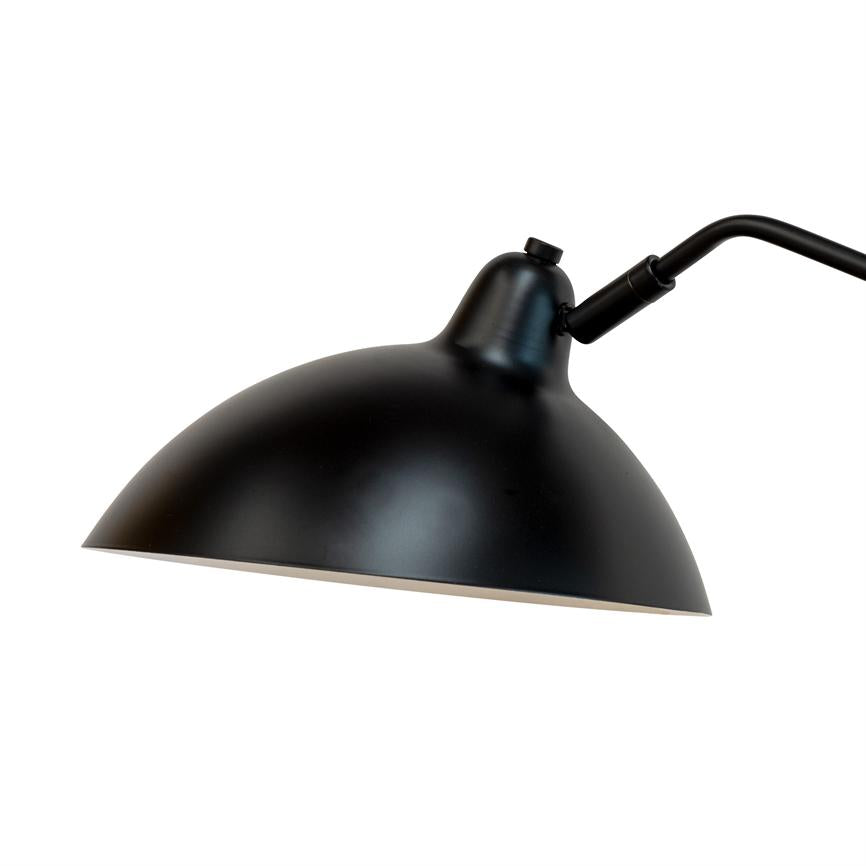 En sort, halvkugleformet skrivebordslampe peger nedad; kuppelen er monteret på et justerbart, buet metalarm; vist isoleret mod en ren hvid baggrund.
