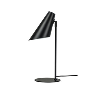 Skrivebordslampe med aflang, skrå konisk skærm, der peger nedad; tynd, lodret stang og rund pladefod i mat sort; strømledning løber ud til siden; isoleret på hvid baggrund.