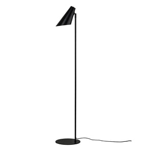 Sort gulvlampe står oprejst, skærm peger skråt nedad; slank metalstang på rund fod med synlig ledning, placeret mod hvid baggrund.