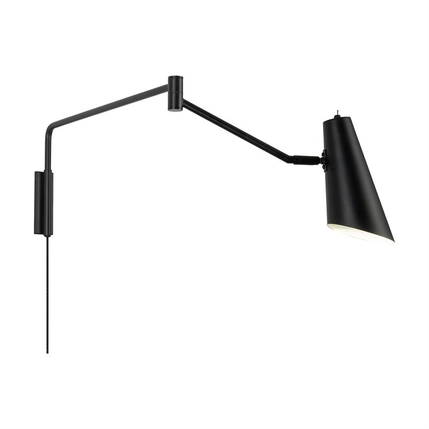 Væglampe med lang, justerbar arm; armen er udstrakt og holder en sort, konisk skærm vippet nedad, lyser til højre; monteret på væg med synligt kabel mod hvid baggrund.