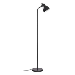 Sort, slank gulvlampe står opret med buet arm og nedadvendt skærm, placeret på rund fod mod ensartet hvid baggrund.