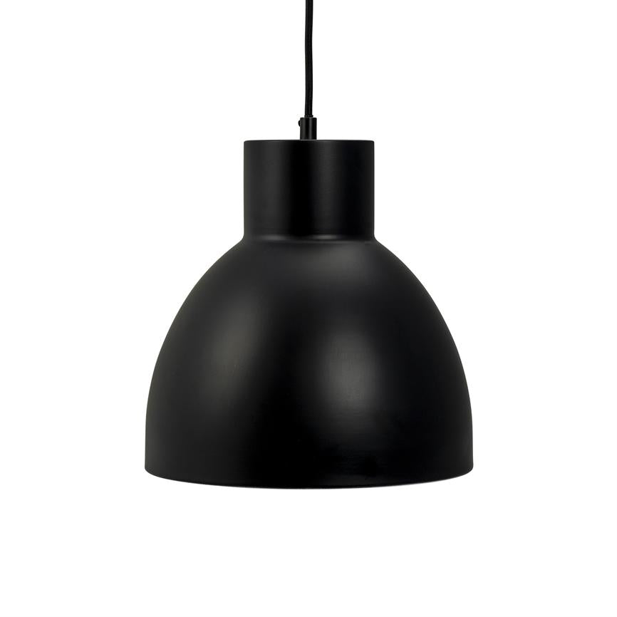 En sort metal pendellampe hænger i en tynd sort ledning; dens matte, runde kuppel afskærmer lyset nedad mod en ren, hvid baggrund i et minimalistisk udtryk.