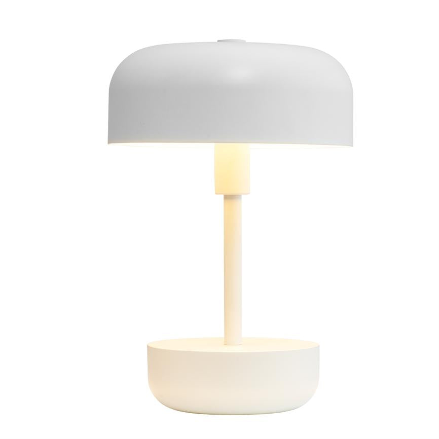 En hvid, minimalistisk bordlampe med rund skærm og skålformet fod udstråler blødt, varmt lys, placeret mod en neutral hvid baggrund.