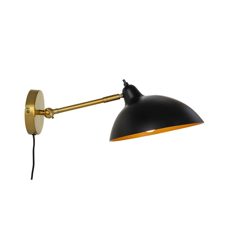 Væglampe monteret på messingbeslag, udtrukket justerbar arm, sort skærm med gylden inderside, peger nedad over en hvid, minimal baggrund.