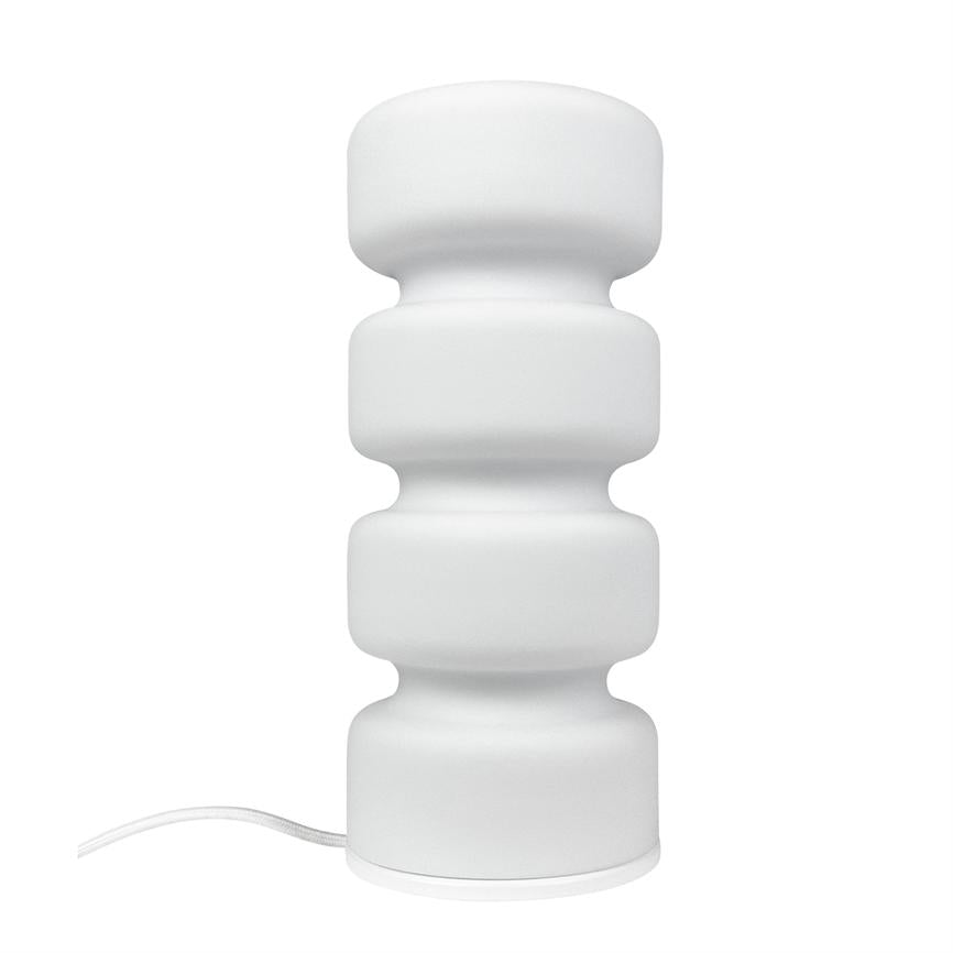 Hvid bordlampe står på hvid baggrund; den består af fire afrundede, stablede sektioner og en synlig hvid ledning, minimalistisk og moderne design.
