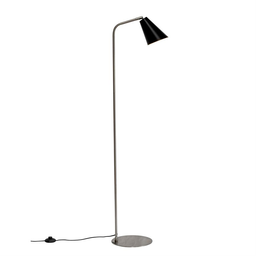 Gulvlampe med slank kromstang og sort, skrå skærm peger nedad; står på rund metalfod med synlig ledning og fodkontakt mod ensartet hvid baggrund.