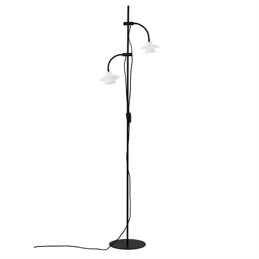 Gulvlampe med slank sort stang, to buede arme bærer hvide skærme; ledning løber ned langs stangen til rund sort fod på hvid baggrund.