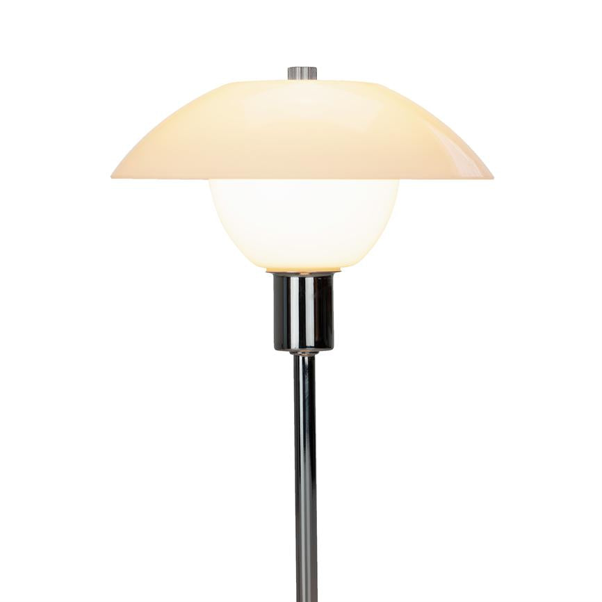 Lampe udsender blødt varmt lys; opal skærm i to niveauer (bred halvkugle øverst, rund globus under) monteret på slank kromstang mod hvid baggrund.
