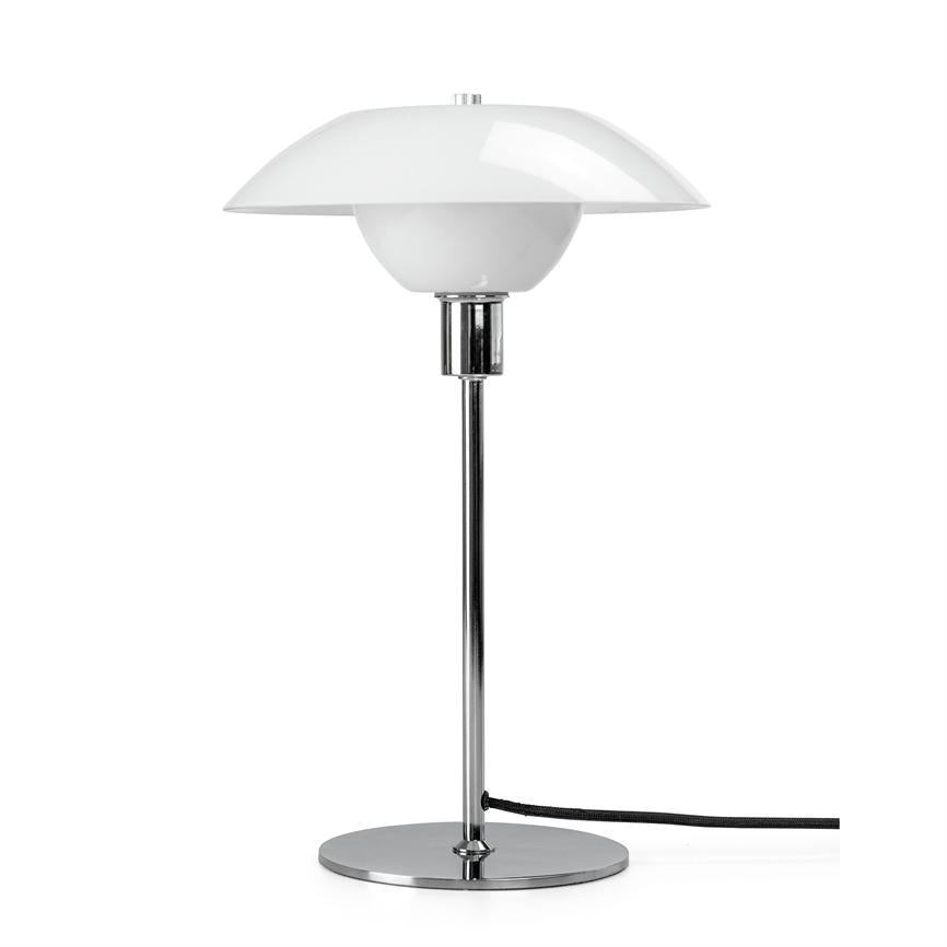 Bordlampe står på rund kromfod, med slank kromstang og hvid dobbelt kuppelskærm; sort ledning ligger på overfladen foran en ensartet hvid baggrund.