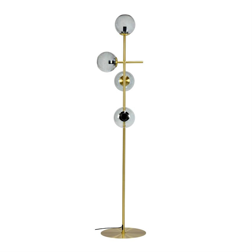Gulvlampe står lodret med tre runde røgfarvede glaskupler monteret langs en slank guldmetalstang, en kort tværarm og rund fod; minimalistisk design på hvid baggrund.