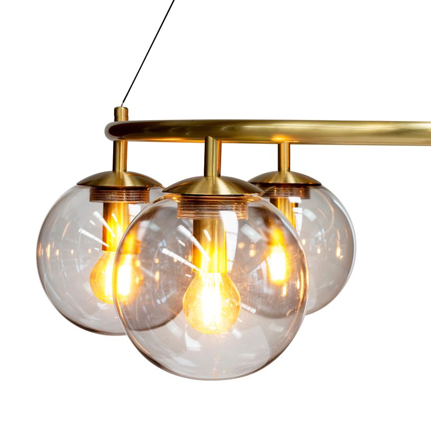 Loftlampe med tre klare glaskupler, hver indeholdende en glødende pære; lampen hænger i en buet messingstang og udsender varmt, gyldent lys mod en hvid, isoleret baggrund.