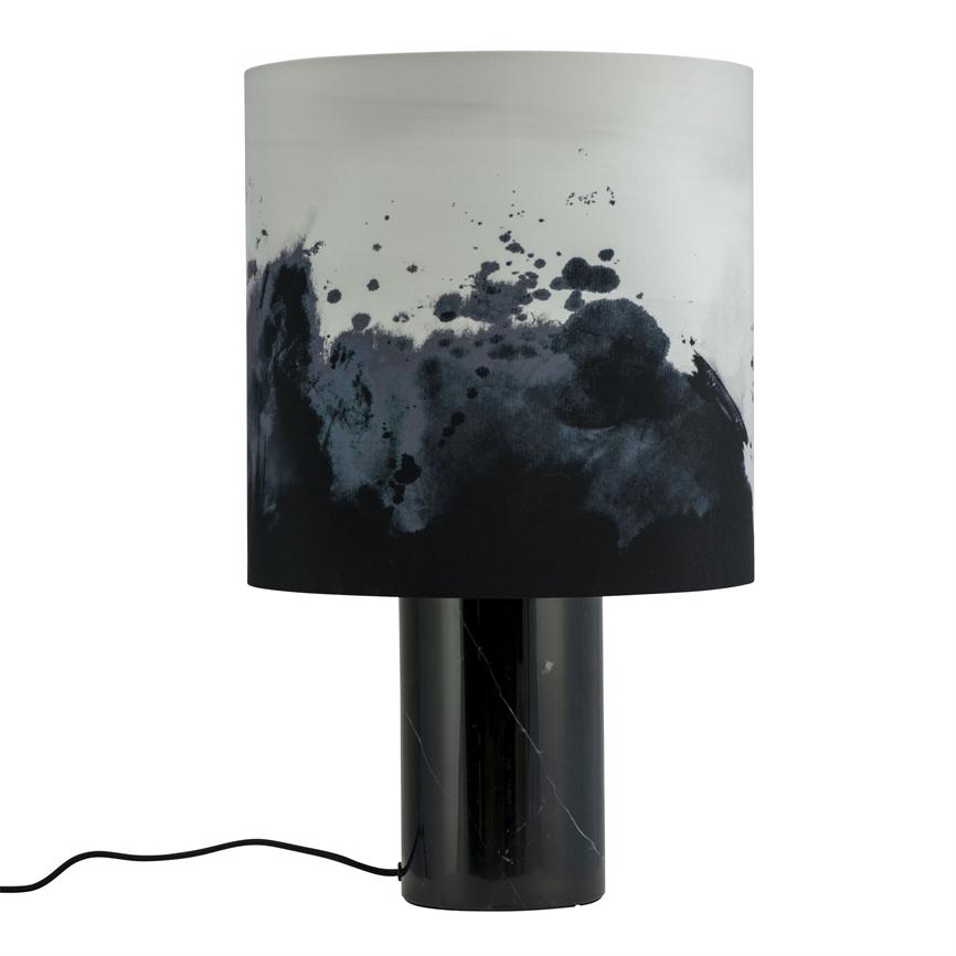 Bordlampe med cylindrisk sort marmorfod og cylindrisk lampeskærm prydet af sorte og grå blækpletter; ledning løber ud til siden. Neutral hvid baggrund.