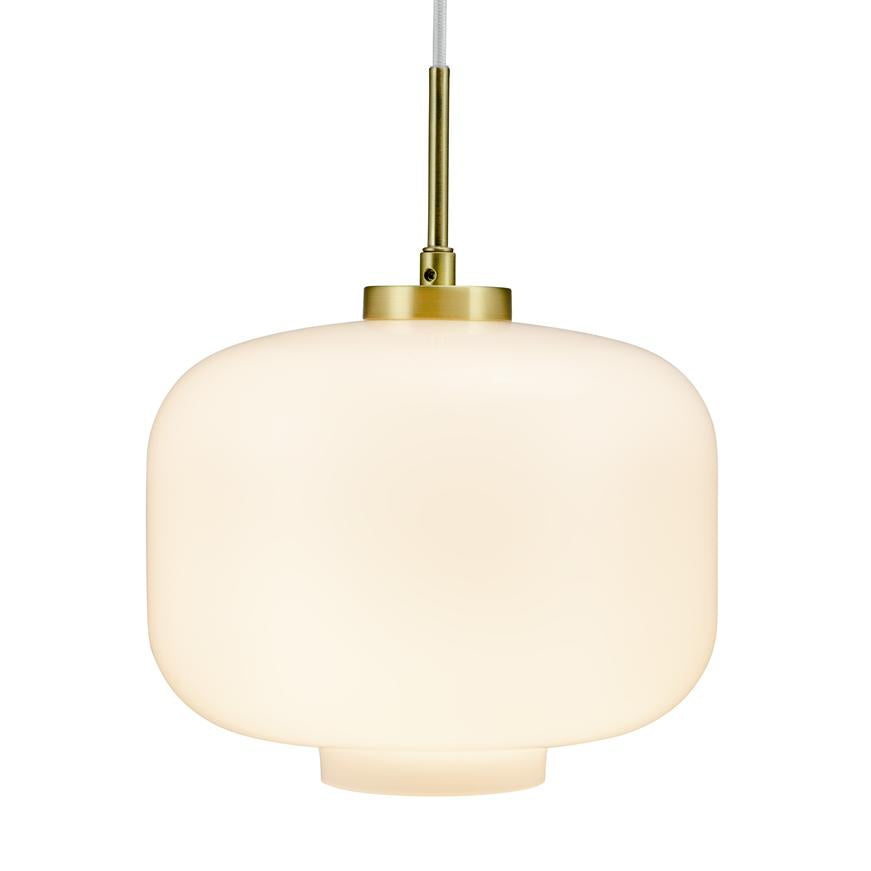 En rund, mat hvid glaspendel hænger i en tynd hvid ledning med messingbeslag; den udsender blødt, varmt lys mod en minimalistisk, neutral baggrund.