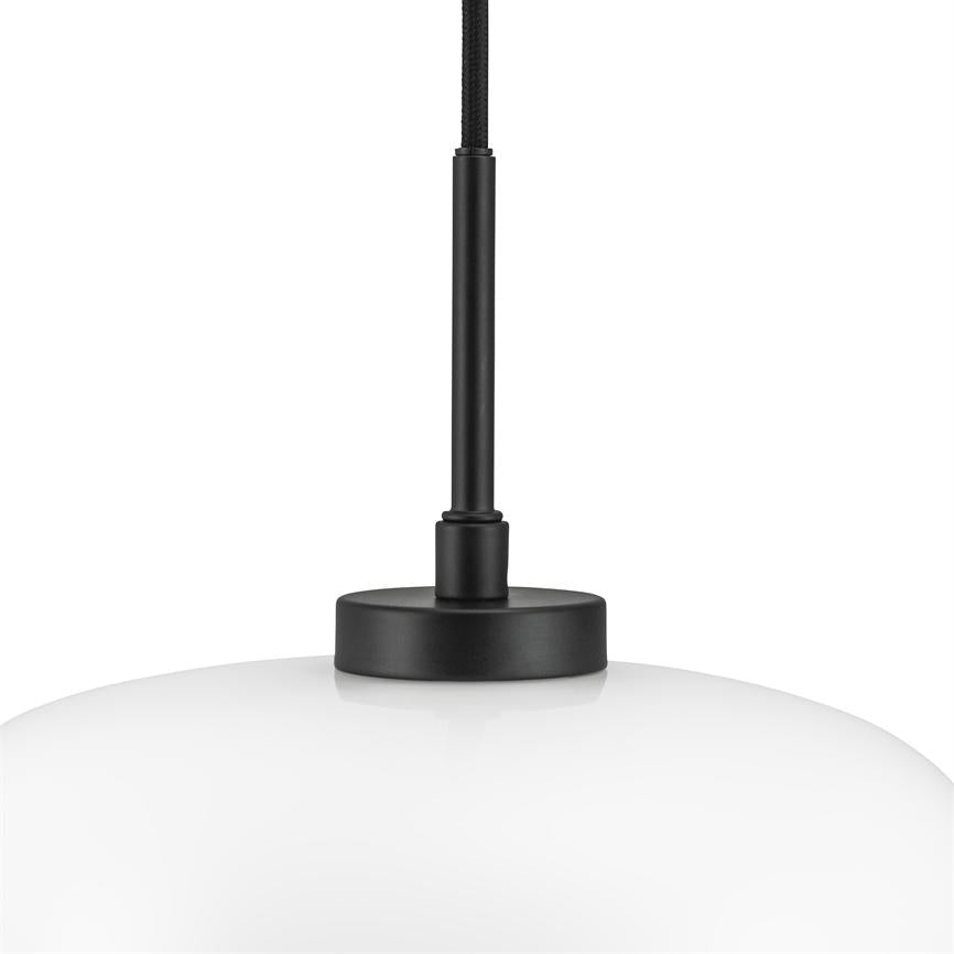 En hvid, rund glaspendel hænger fra et sort stofbeklædt kabel; en sort metalstang og rund metalkappe forbinder skærmen til loftet mod en neutral hvid baggrund.