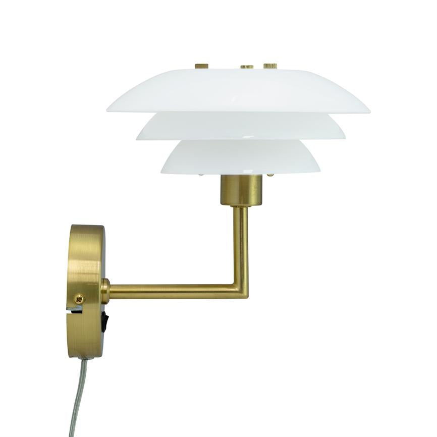 Væglampe med tre hvide, stakkede skærme; arm i børstet messing strækker lampen ud fra en rund vægbasis; ensartet hvid baggrund og synlig ledning.