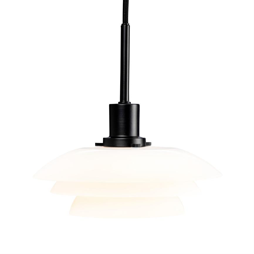 En hvid, flerlags lampskærm med sort fatning hænger og udsender blødt, diffust lys mod en ensartet hvid baggrund.