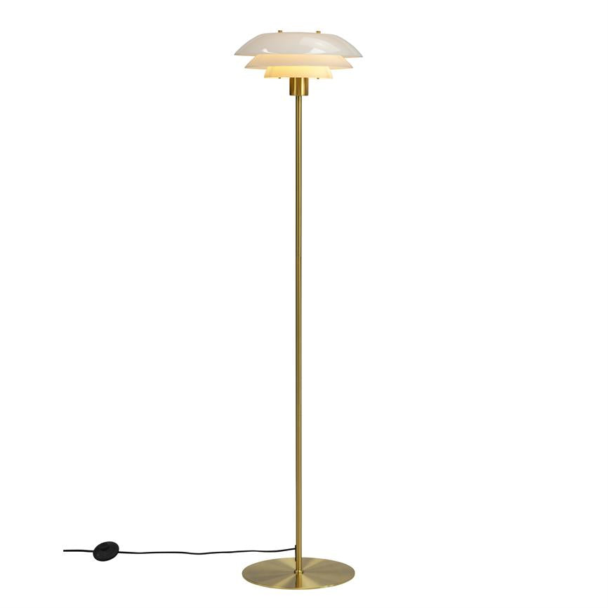 Gulvlampe med tre hvide skærme udsender varmt lys; står på en slank messingstang med rund fod og sort ledning mod hvid, neutral baggrund.