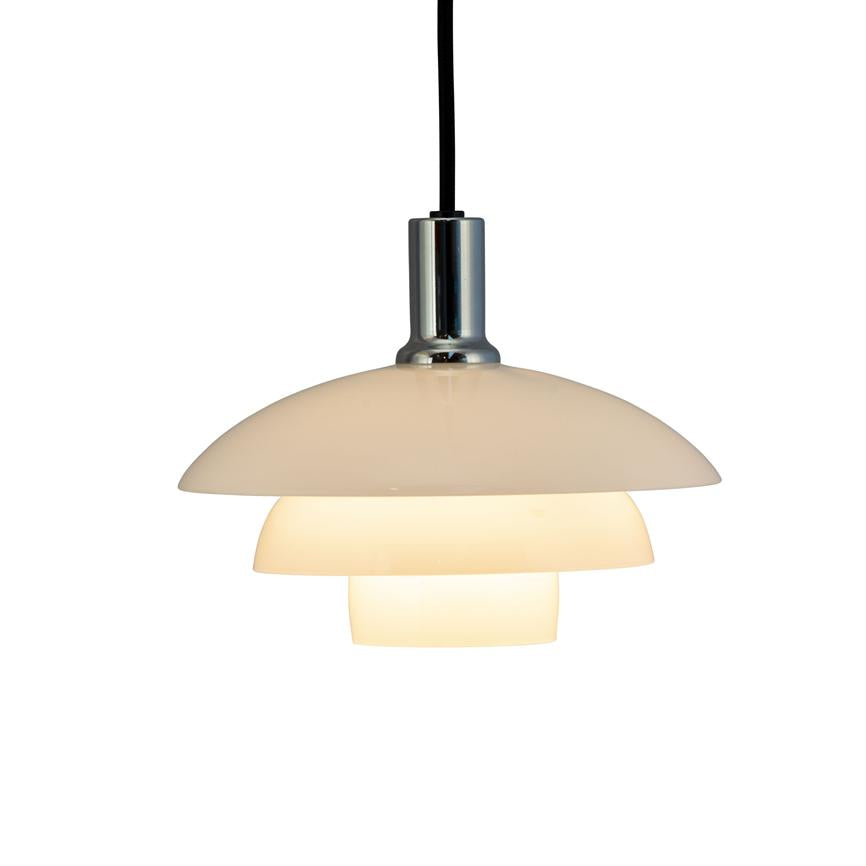 Pendellampe hænger i sort led og udsender varmt, diffust lys gennem tre stablede hvide skærme; kromfatning øverst, enkel moderne stil mod hvid baggrund.