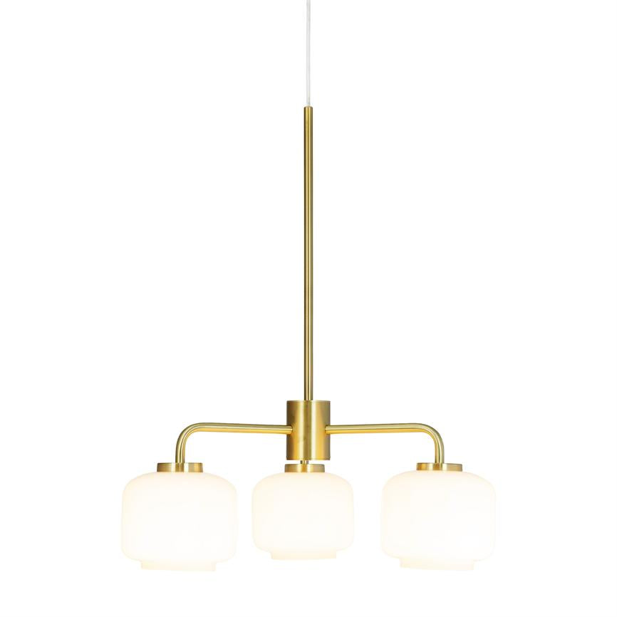 En moderne loftslampe med tre matte hvide glaskupler hænger fra en slank guldfarvet stang og udsender et blødt, diffust lys mod en neutral, hvid baggrund.