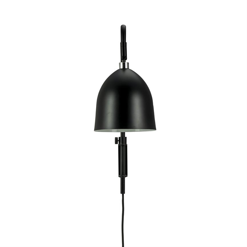 Sort væglampe hænger monteret med kuppelformet skærm, retter lyset nedad; har justerbar arm og synlig sort ledning mod en neutral hvid baggrund.