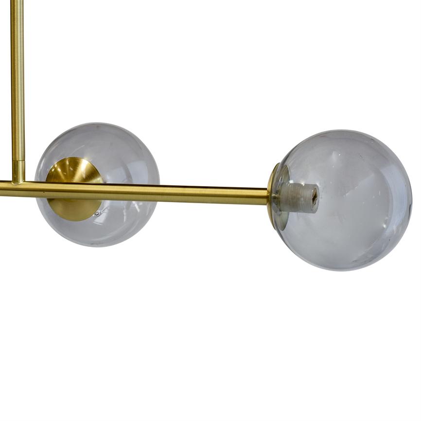 En moderne loftslampe: to klare glasglobusser monteret på en horisontal messingstang, den ene globus uden pære, stangen er ophængt lodret mod en neutral hvid baggrund.