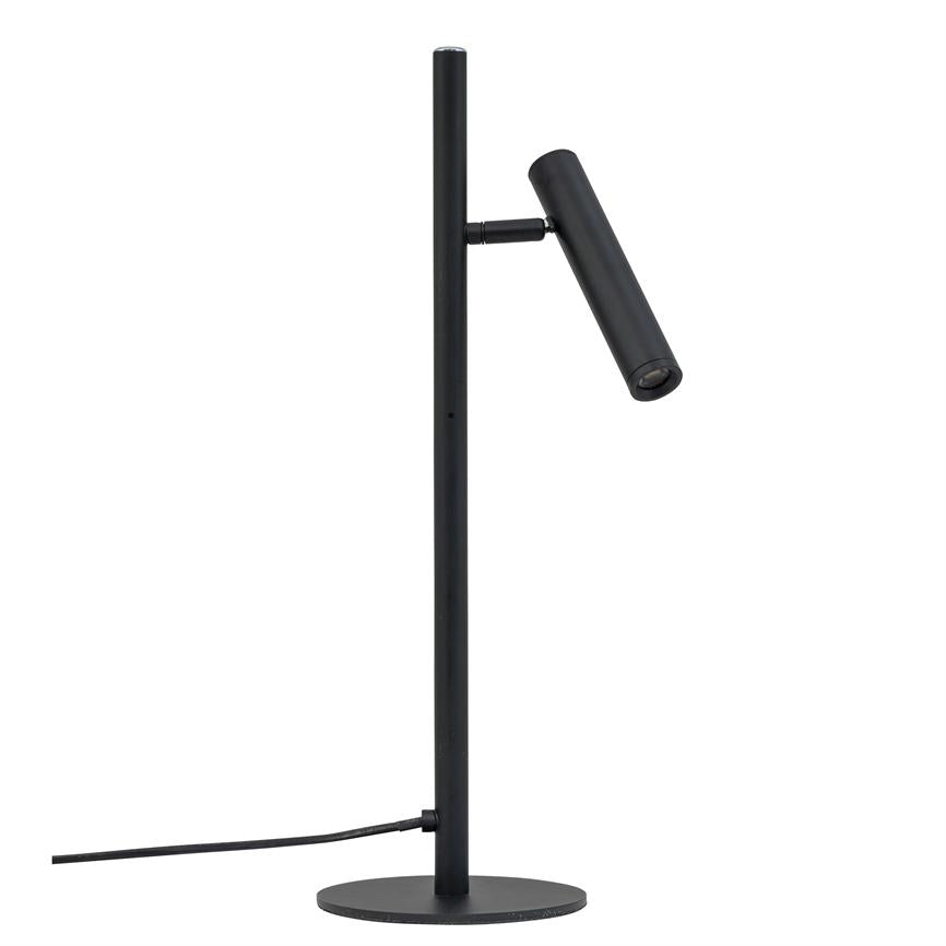 En slank sort bordlampe med cylindrisk, justerbar lampehoved, der peger skråt nedad; monteret på en lodret stang og rund fod, med synlig strømkabel på hvid baggrund.