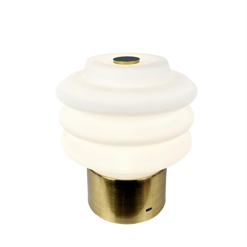 Bordlampe med ribbet hvid opalglaskuppel, udsender blødt varmt lys; hviler på cylindrisk børstet messingfod med lille USB-port, mod neutral hvid baggrund.