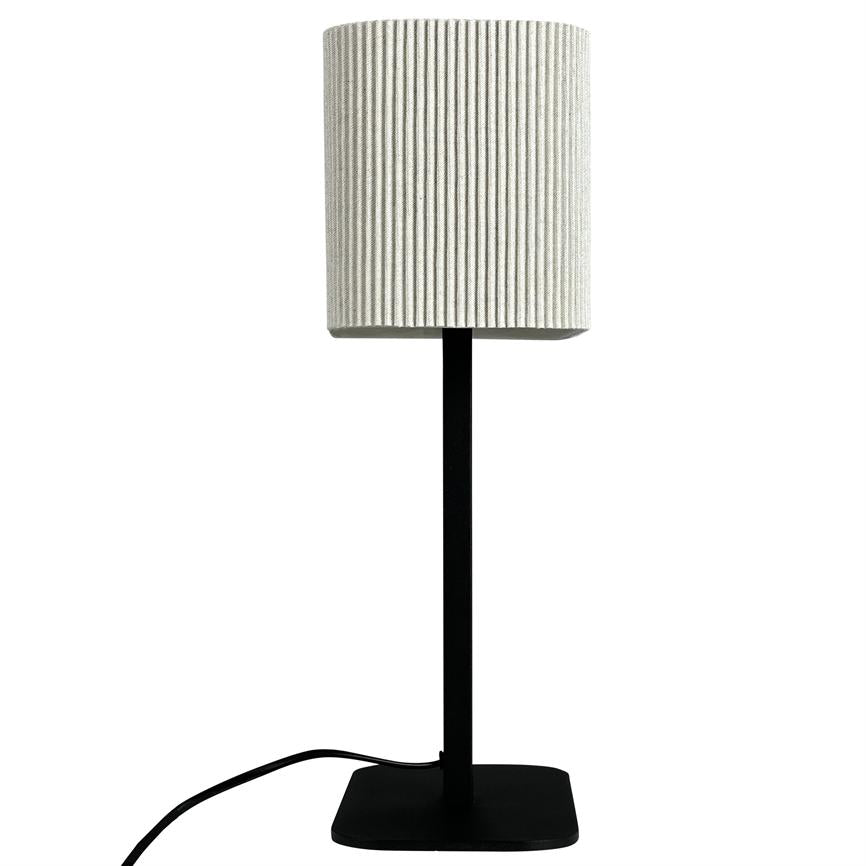 Lampe står lodret på en sort, firkantet fod med tynd stang; en hvid, rillede cylindrisk skærm sidder øverst, og en sort ledning løber langs hvid baggrund.
