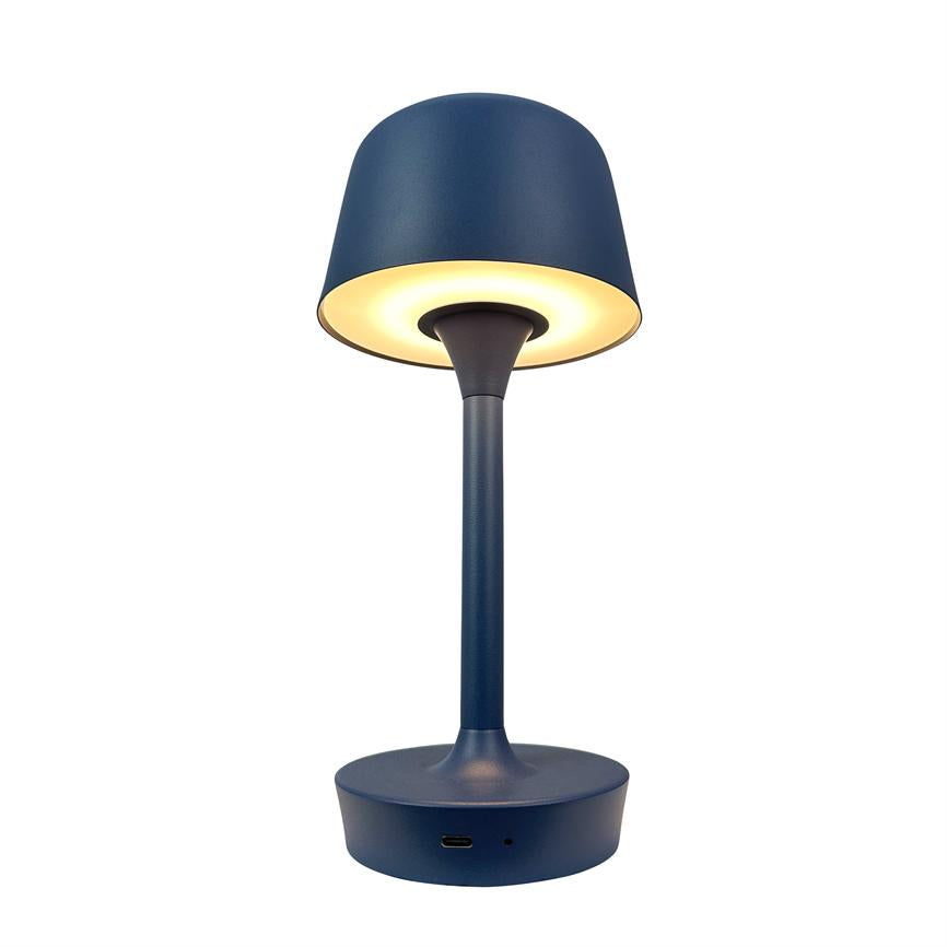 En blå bordlampe udsender varmt, nedadrettet lys fra en rund skærm; den står på en cylinderformet fod med USB-C-port i et hvidt, isoleret studie-/produktfoto.
