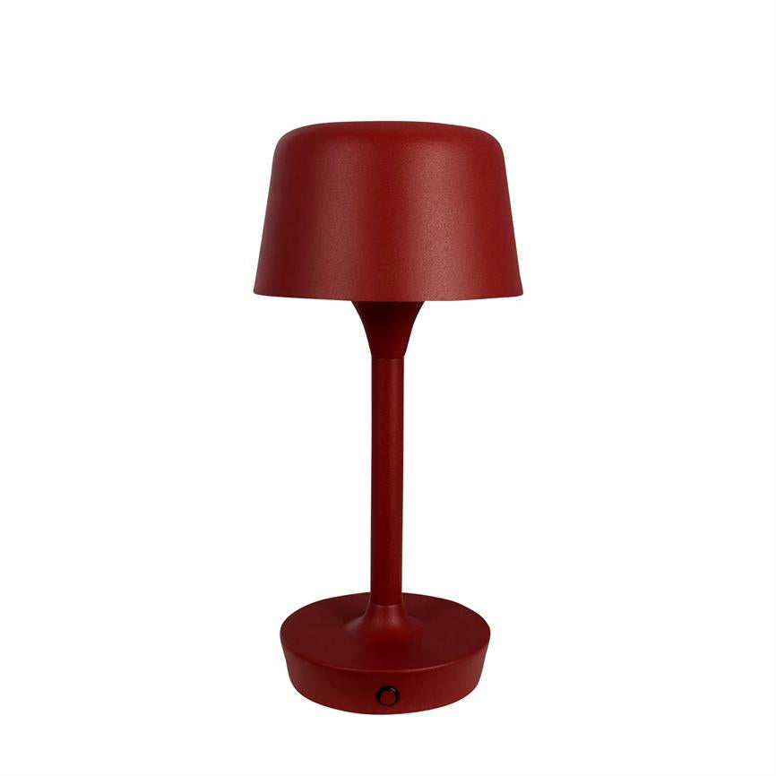 Rød bordlampe står lodret med cylindrisk fod og let klokkeformet skærm; den er ensfarvet, slank i metaldesign og vises mod en neutral hvid baggrund med lille sort knap på basen.