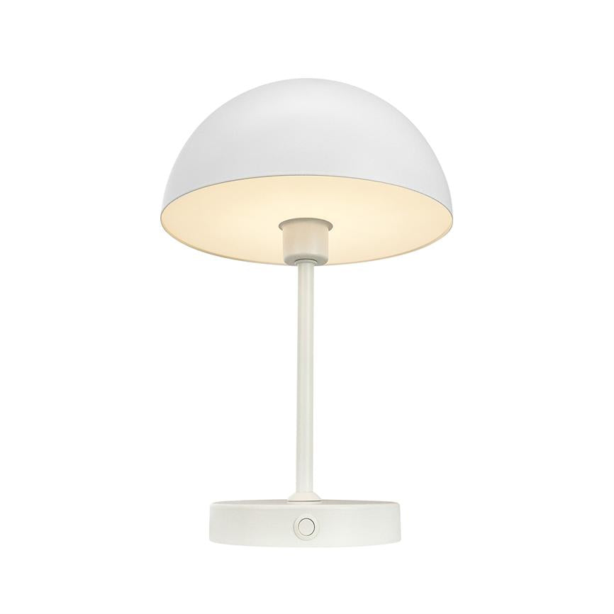 Hvid bordlampe med halvkugleformet skærm, slank stang og rund fod med knap; skærmen er tændt og kaster blødt, varmt lys mod en neutral hvid baggrund.